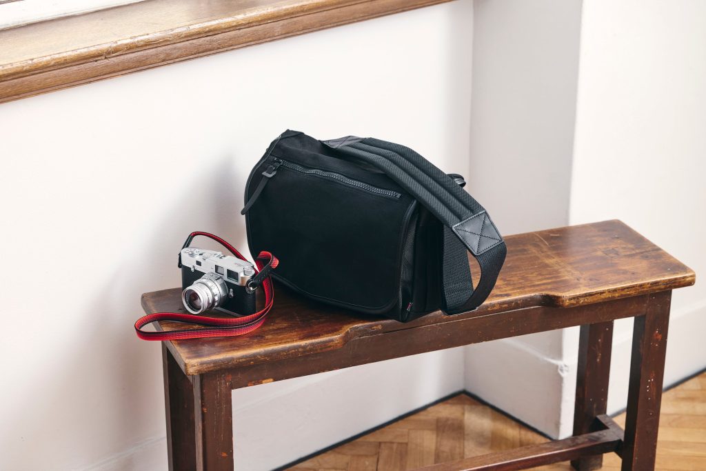 Hướng Dẫn Phụ Kiện Cho Dòng Máy Leica 1 Túi đựng máy ảnh Artisan & Artist ACAM-E màu xanh navy với phụ kiện nhiếp ảnh cao cấp từ Nhật Bản trên bàn gỗ